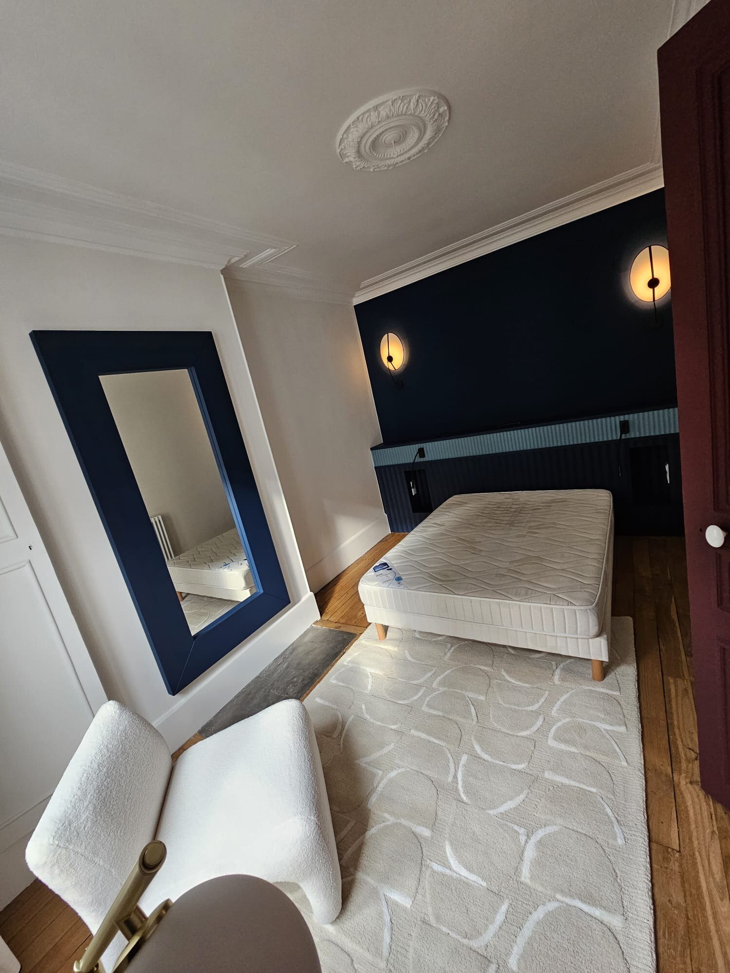 Chambre avec pan de mur bleu nuit et appliques rondes